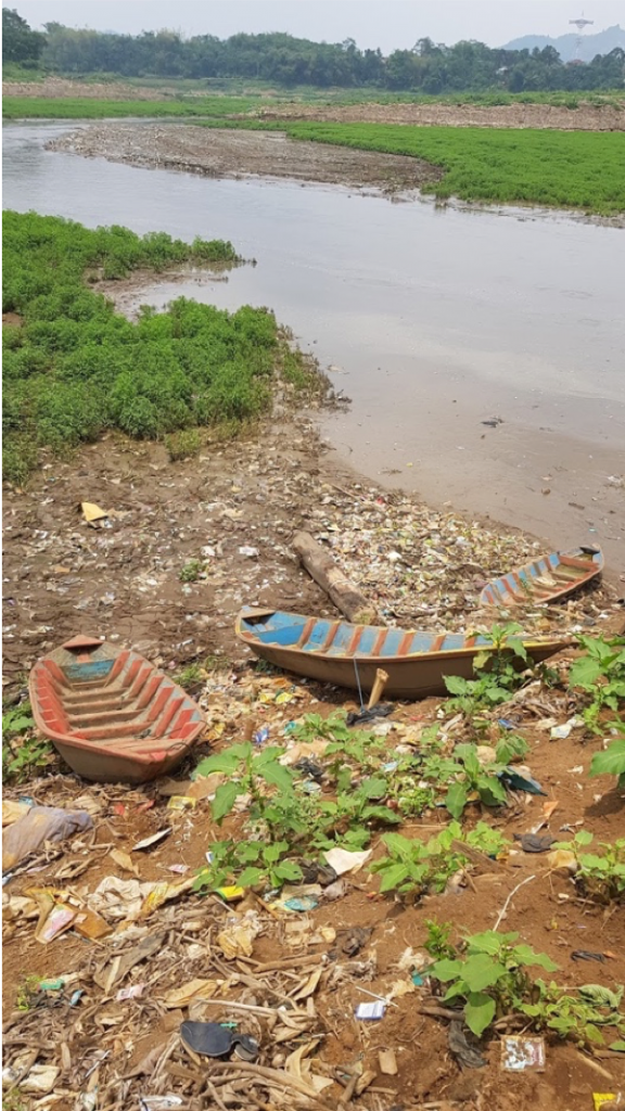 <p>Fishing boats waiting to be taken out on the river, surrounded by waste.</p>
