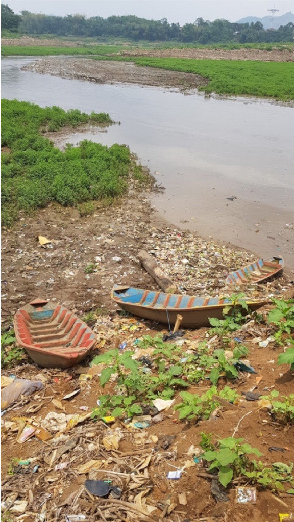 Fishing boats waiting to be taken out on the river, surrounded by waste.